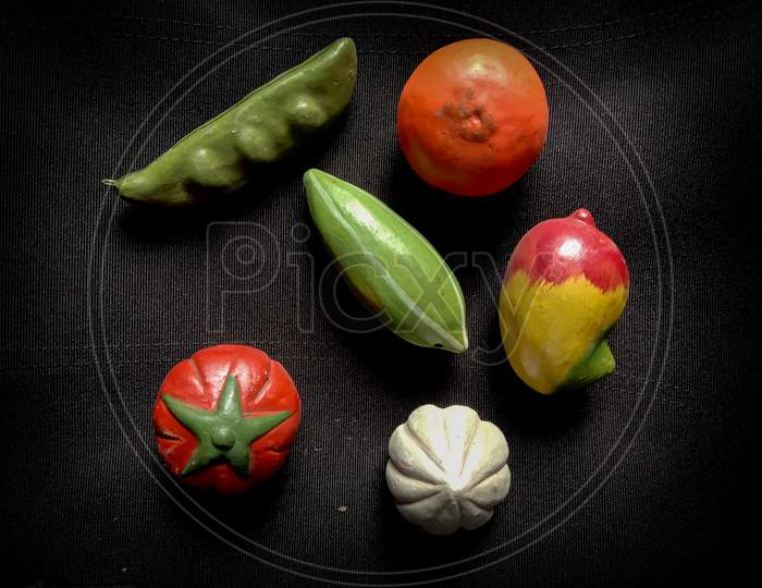 some toy fruits and vegetables in black background with some selective focus