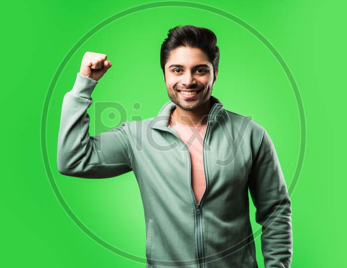 Indian handsome man with success gesture, standing isolated over green background