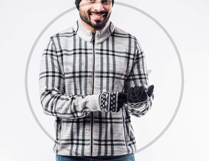 Indian bearded man in winter clothing presenting or standing isolated over white background