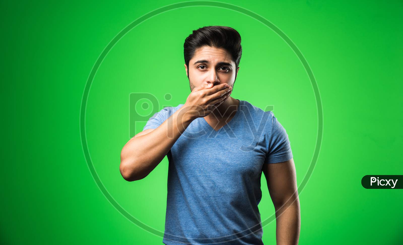 Handsome Indian / asian depressed man standing isolated over green background looking stressed and nervous having  Anxiety probl