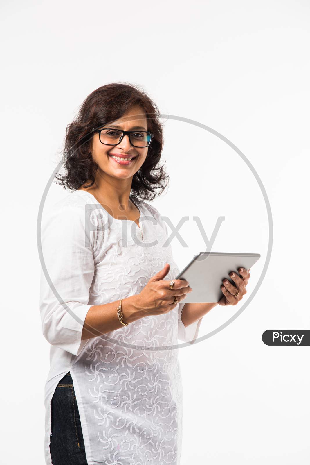 indian lady/women using tablet pc while standing isolated over white background, selective focus