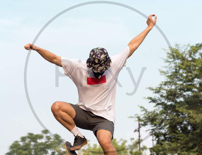 A Young Adult Wearing A Protective Mask While Doing An Ollie Stunt On His Skatebaord.