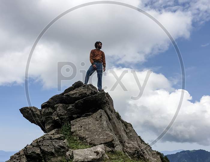 Portrait of a handsome young guy standing on cliff in the height of a mountain in hilly area of Himachal Pradesh, India