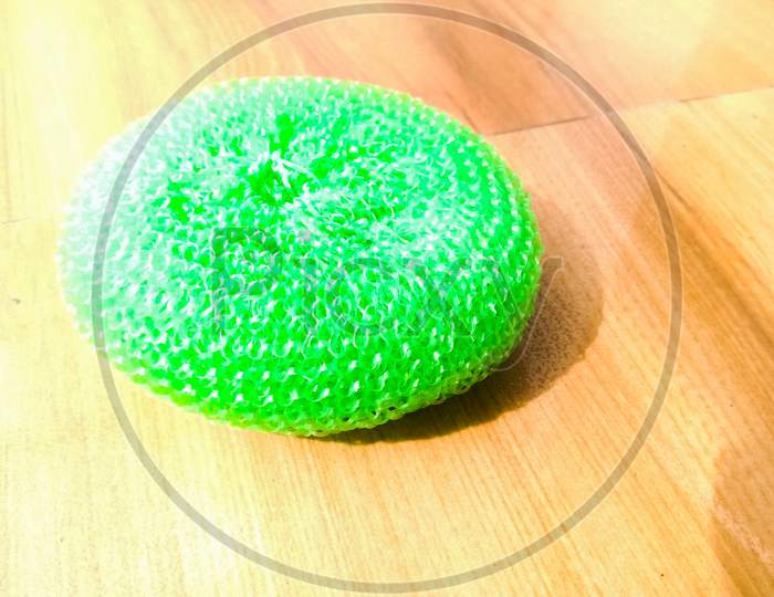 A Green Plastic Scrubber Placed On Floor.