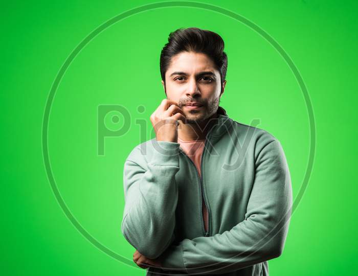 Handsome Indian / asian depressed man standing isolated over green background looking stressed and nervous having  Anxiety probl