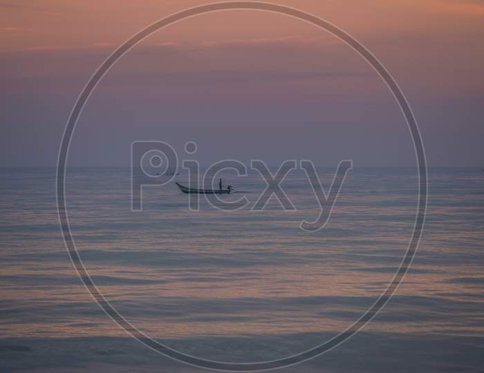 Silhouette of a fishing boat in setting sun by the sea