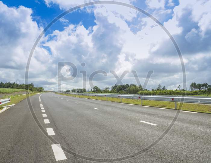 Dual carriageway with blue cloudy sky.