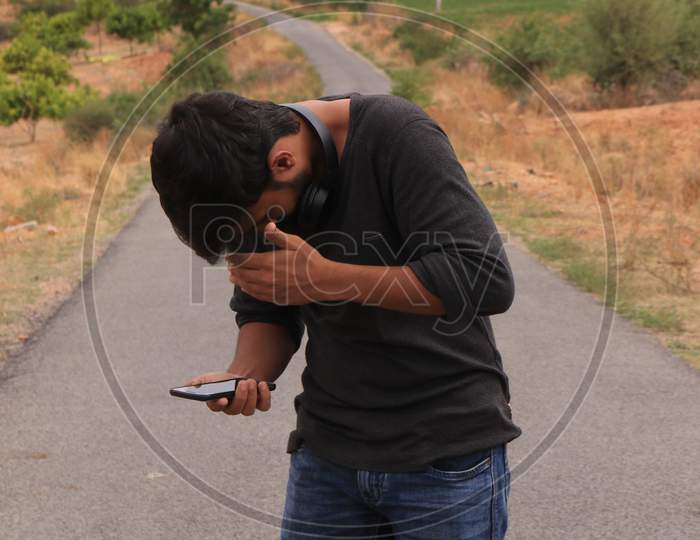 Young Indian Man using a Smartphone or Mobile Phone with Headphones on