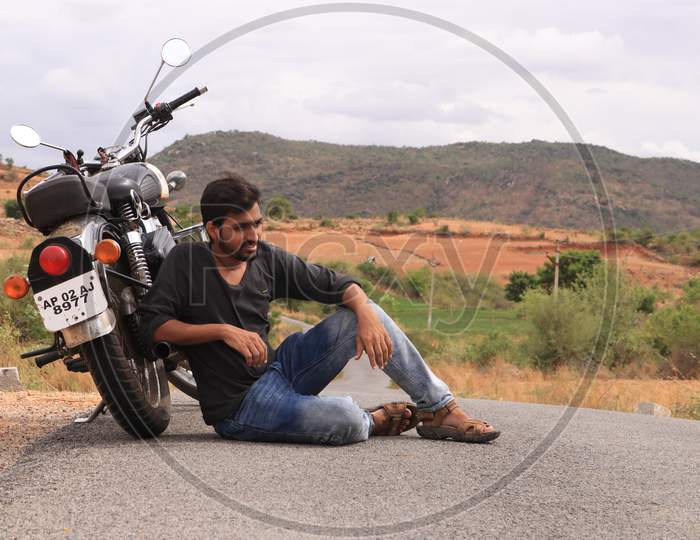 Young Indian Man on a Single Lane Road with a Bike