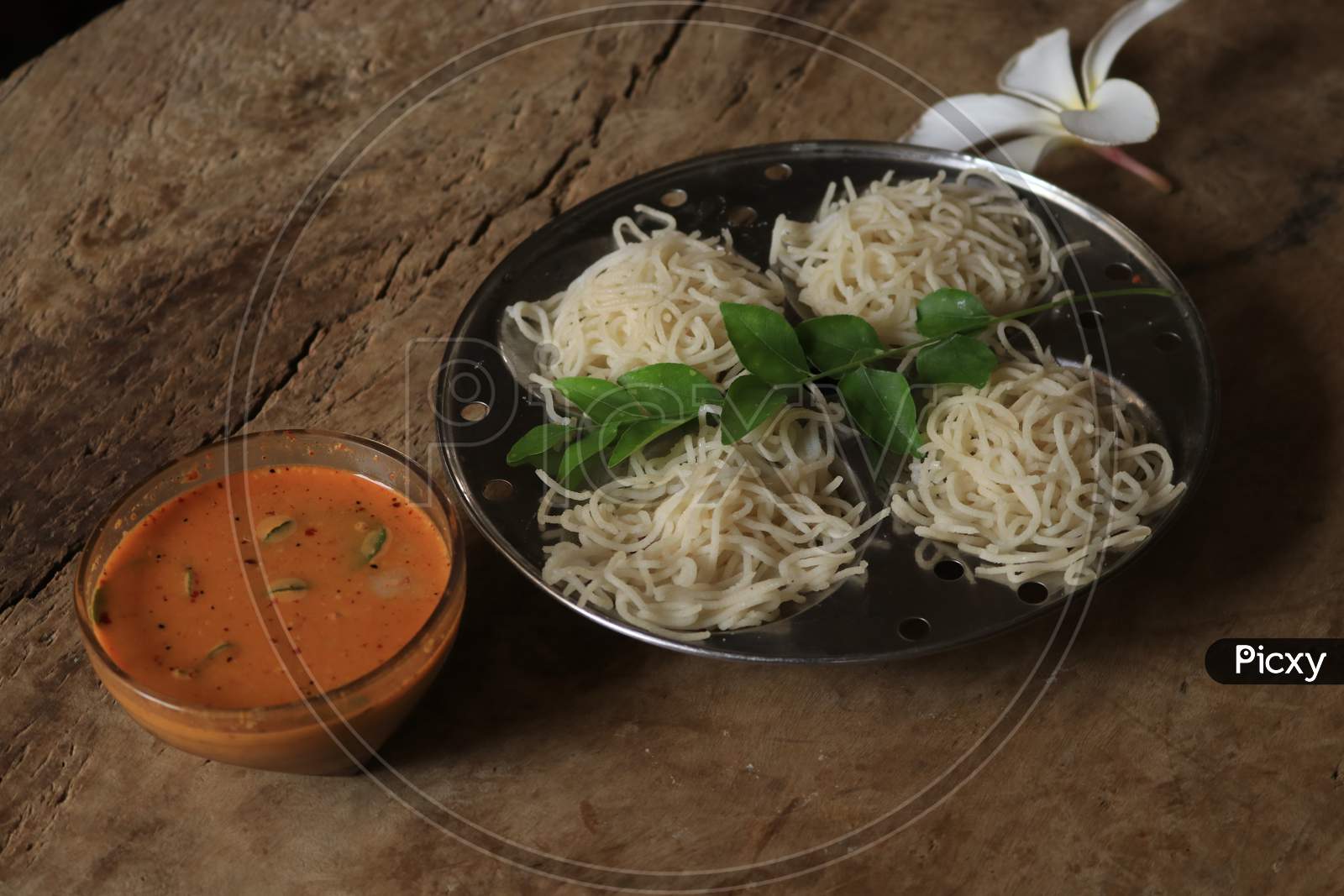 Rice Noodles in Idly Plate with Curry Isolated with Wooden Background