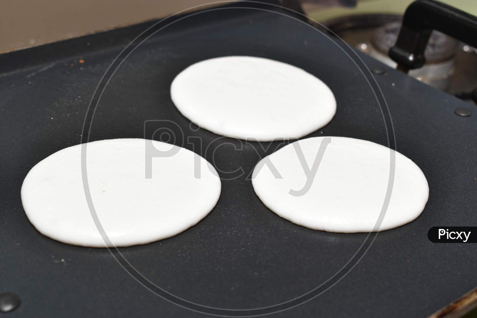 Circular Round Utappam Made Up Of White Batter On Hot Non Stick Pan