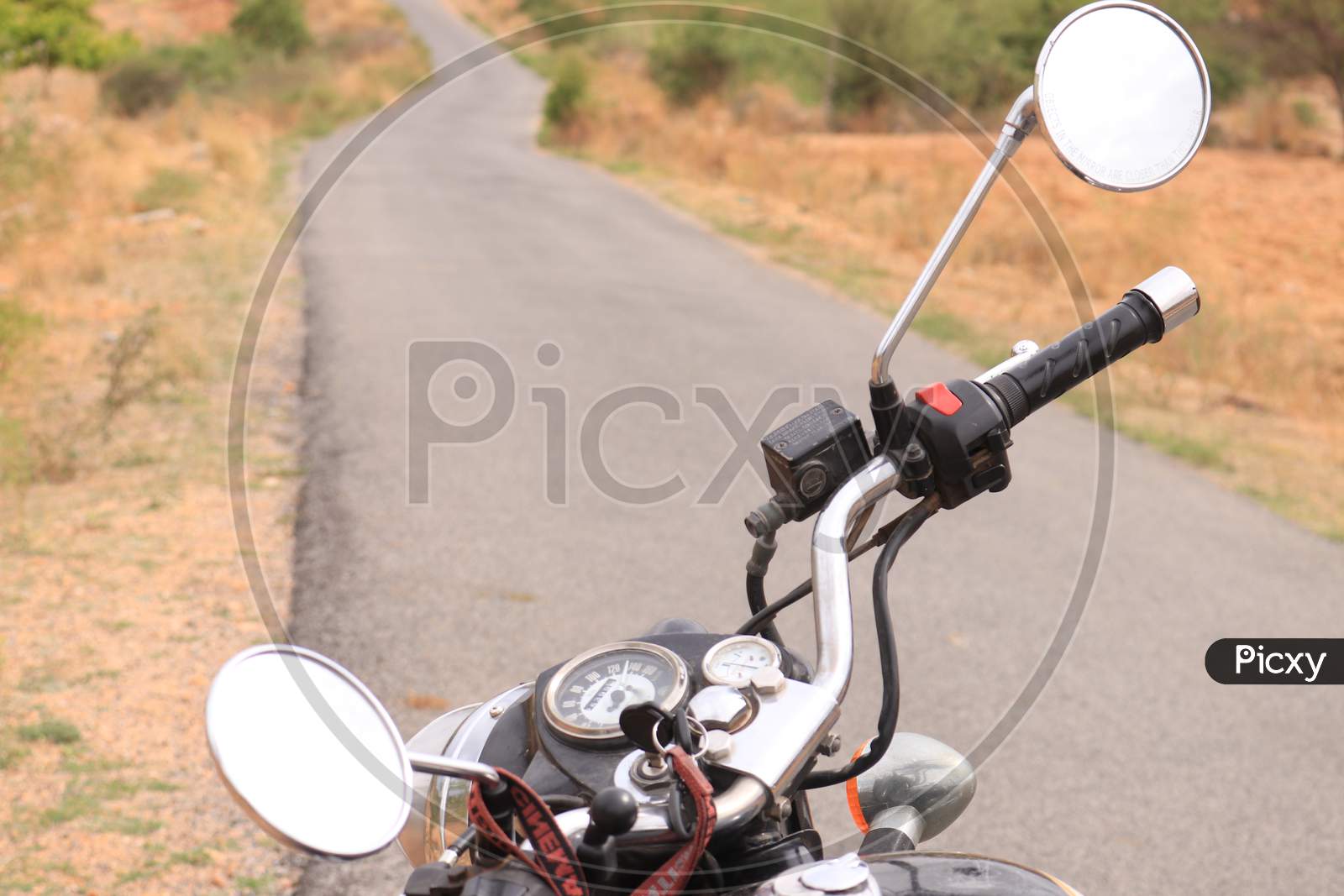 Selective on Royal Enfield Bike Handle with Single Lane Road in the Background