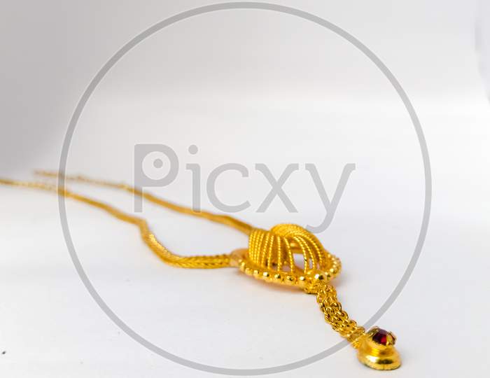 A Golden Necklace Placed Isolated In A White Background.