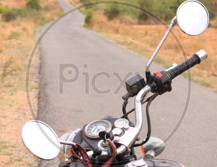 Selective on Royal Enfield Bike Handle with Single Lane Road in the Background