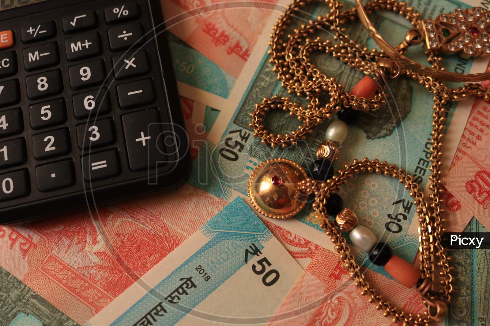 Indian Currency Notes with Calculator and Gold Ornaments