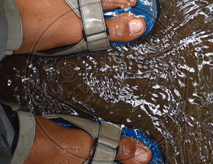 Mens foot wearing sandals under water.