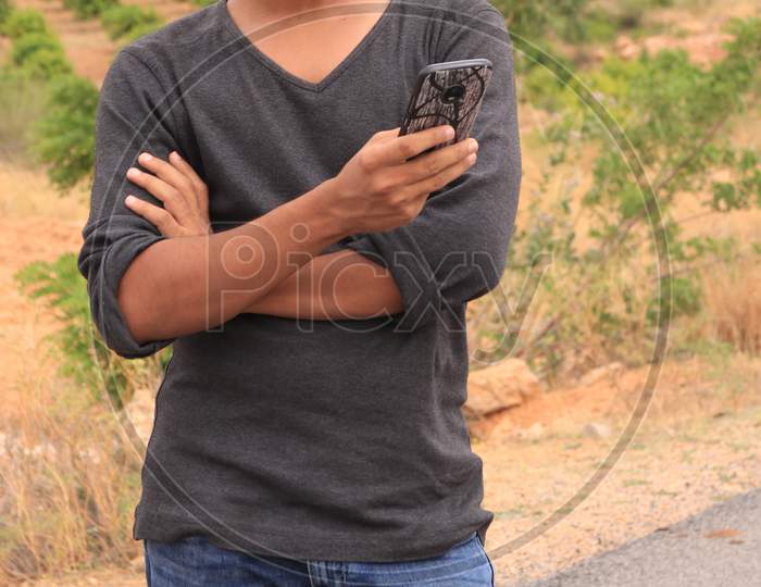 A Young Indian Man using a Smartphone or Mobile Phone with Headphones on