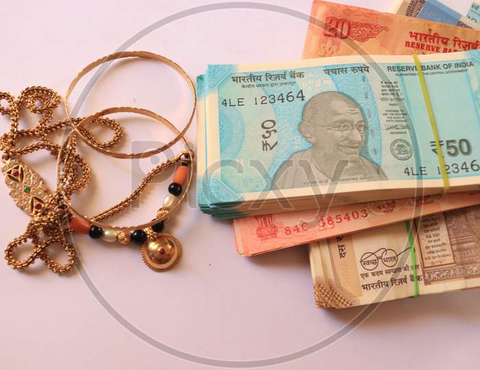 Indian Currency Notes with Gold Ornaments isolated with White Background