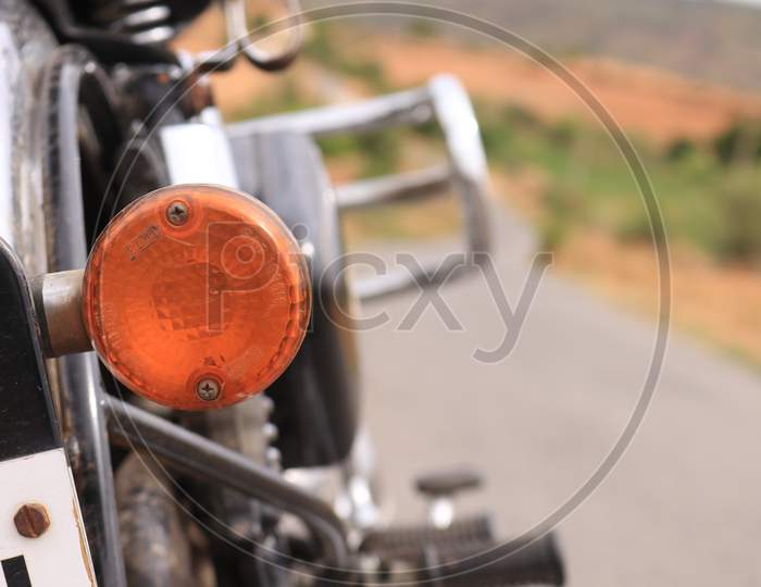 Selective on Royal Enfield Bike Indicator with Single Lane Road in the Background