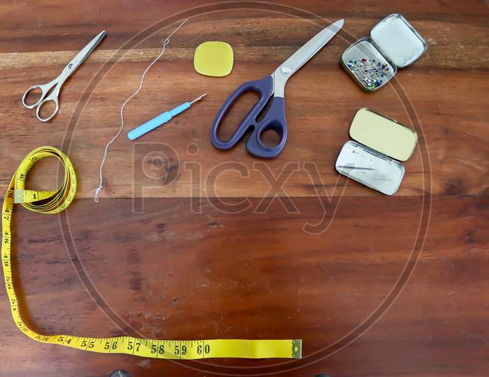Sewing concept. Different sewing accessoires on a brown wooden background.
