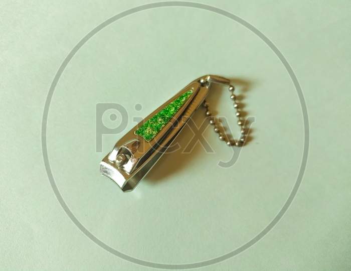 Steel nail clipper isolated on mint color background. Green design on top and ball chain for hang.