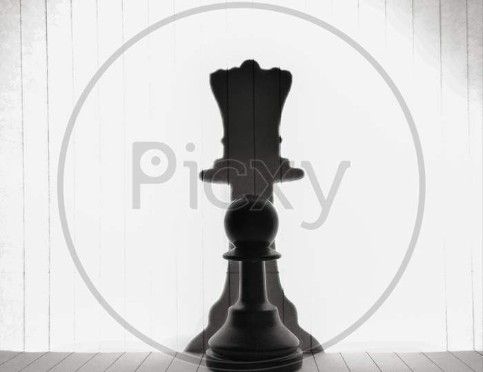 Chess pawn with shadow of queen