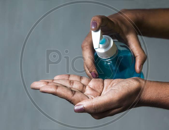 Blue coloured gel sanitiser pumping with finger to squeeze of the gel to wash the hand