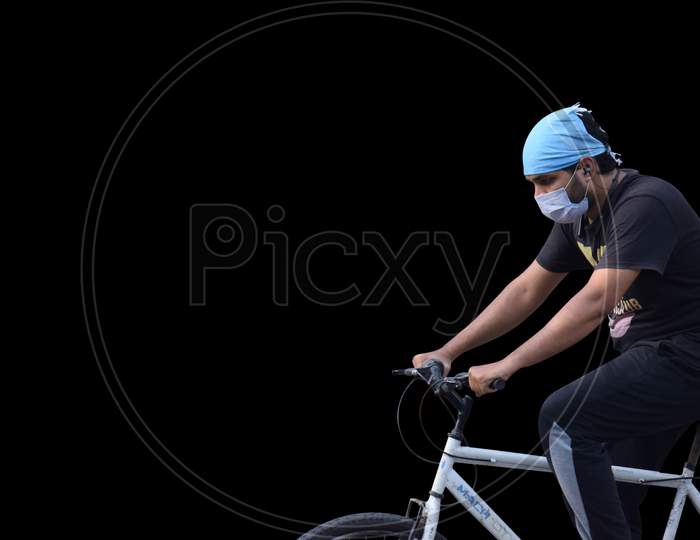 Hyderabad, Telangana, India. June-29-2020: Man With Protective Safety Mask On His Face Riding A Bicycle, Isolated On Black Background