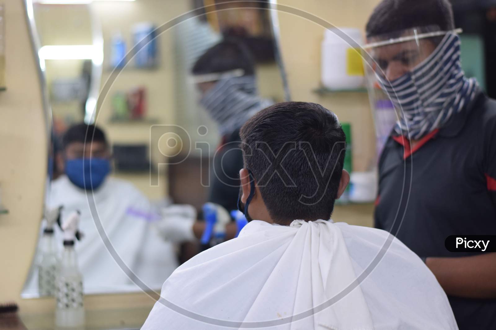 Hyderabad, Telangana, India. july-14-2020: A hairdresser, wearing a protective face mask, works in a barber shop. Reopen after Lockdown for covid-19.