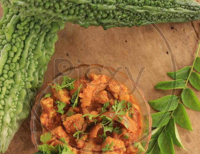 Bitter Gourd Curry in a Bowl with Bitter Gourd Vegetables isolated with Wooden Background