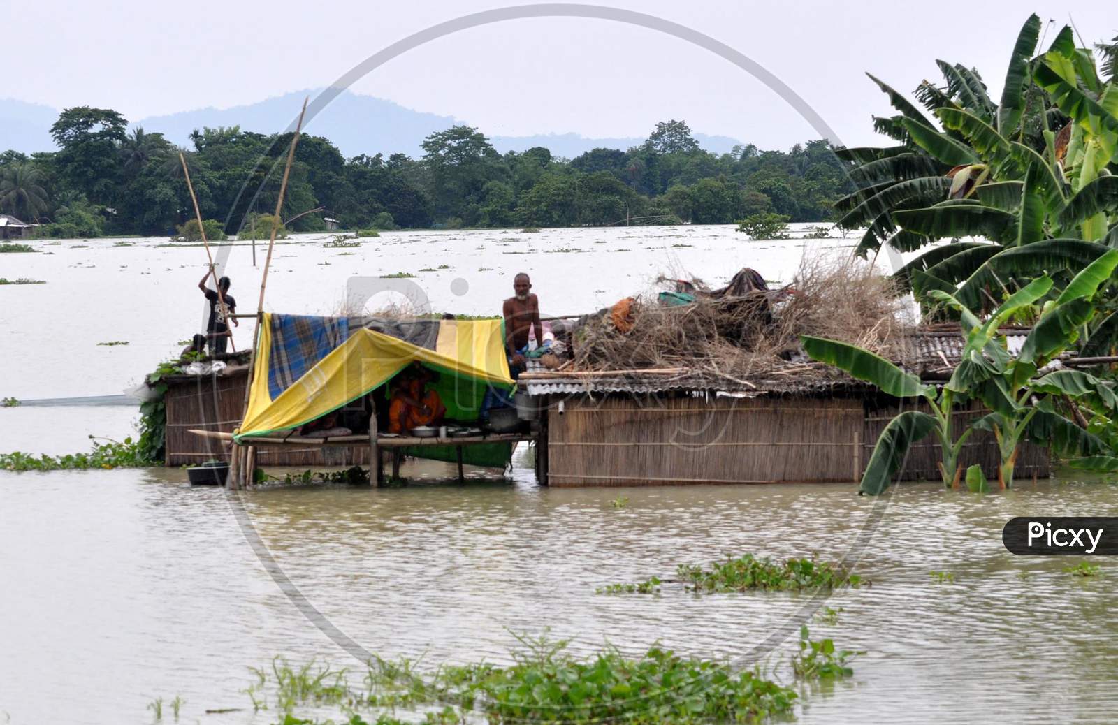 A family gets stranded off on the top of a hut in the flood-affected areas of Pavakity village in Morigaon, Assam on July 1, 2020