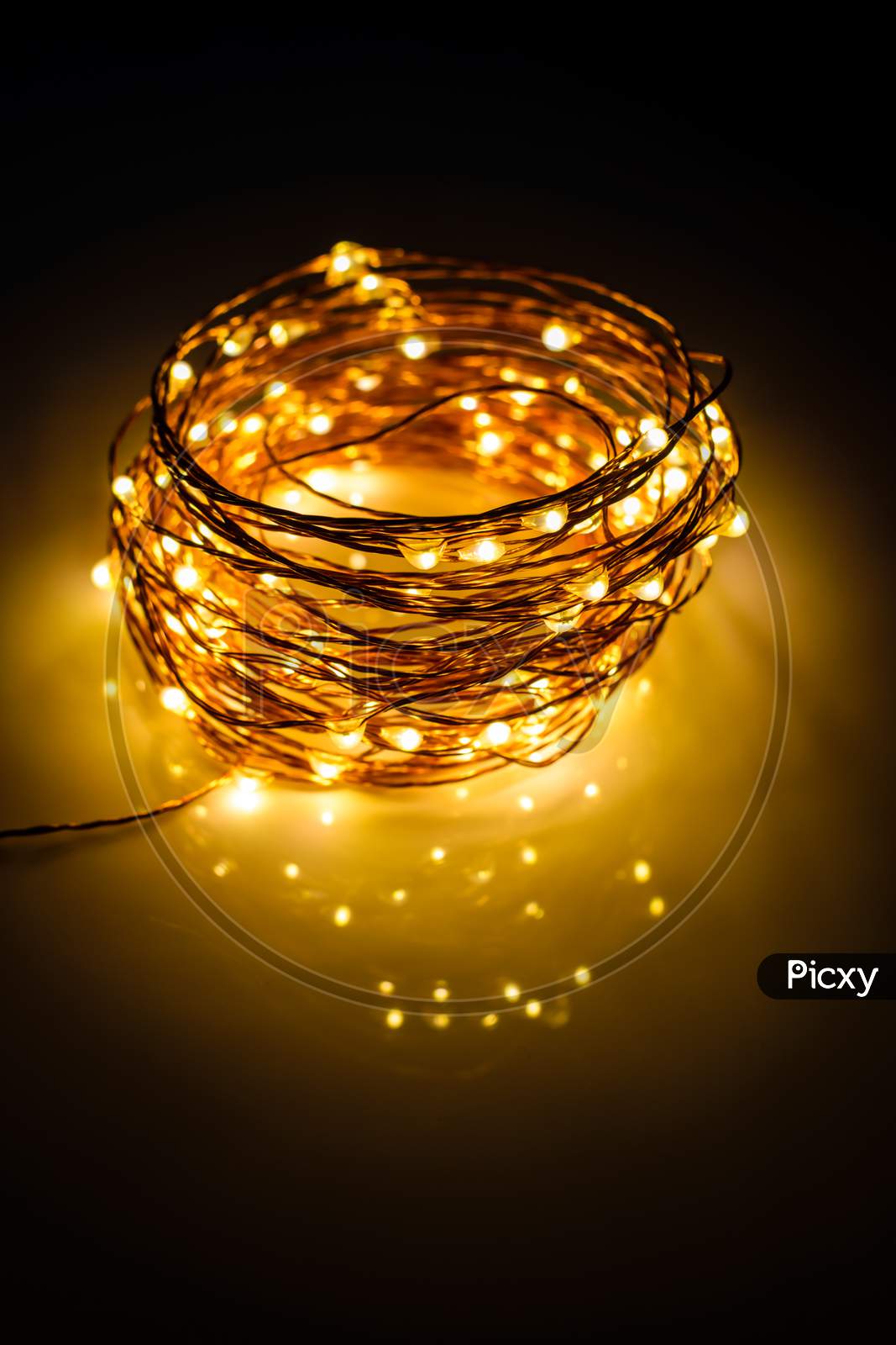 Yellow Colored Light Chain For Decoration Placed On A Reflective Surface. Portrait View