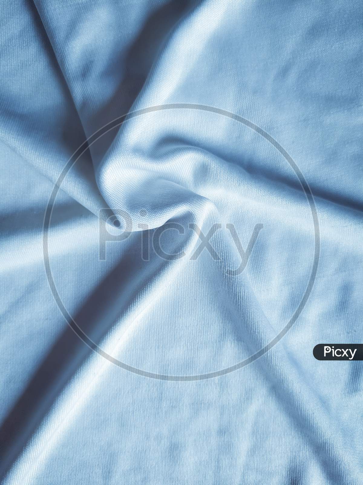 Star like circular shape pattern on silk fabric, handmade foldings on cloths, elegant blue toned. Useful for wallpaper.