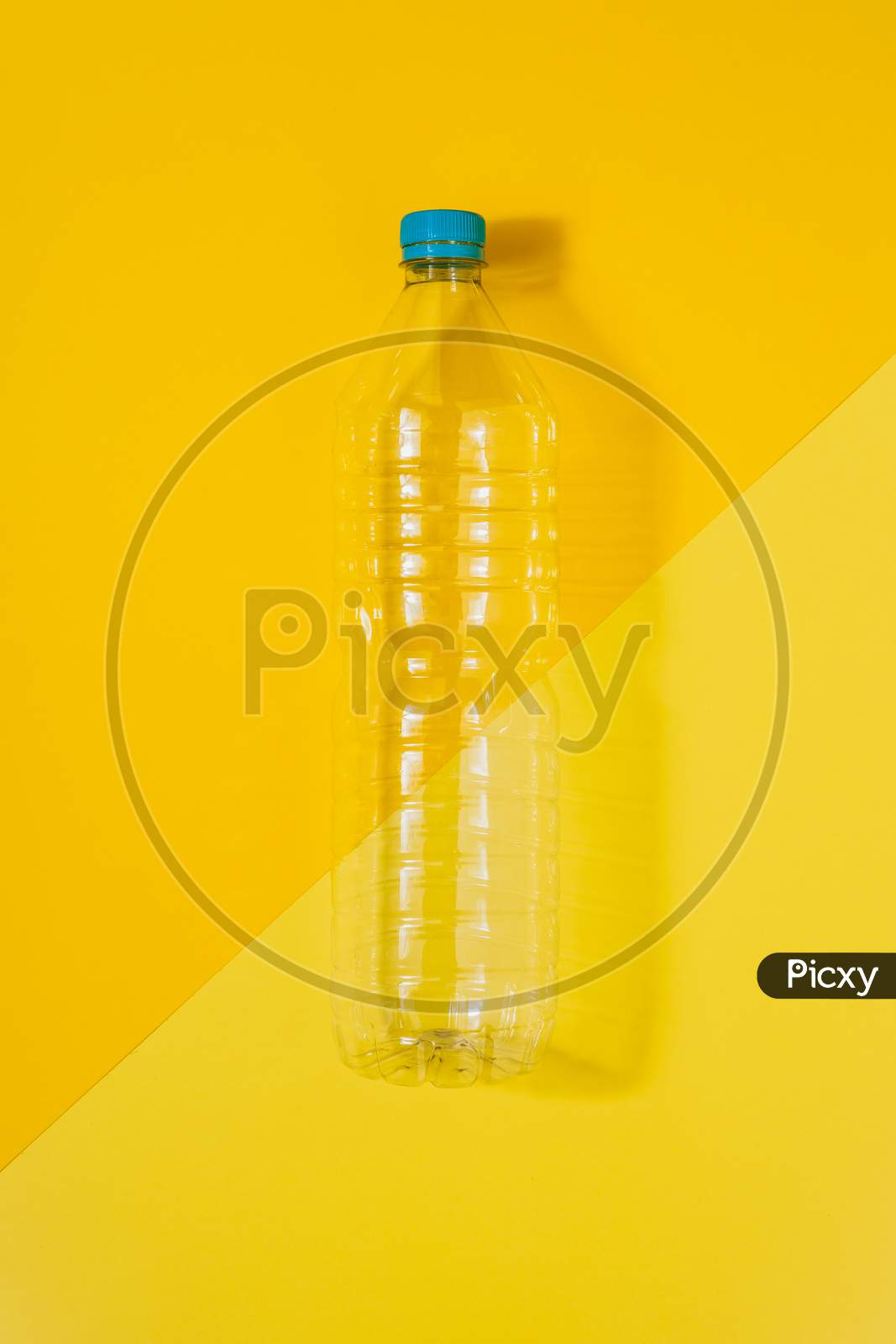 Clear Plastic Bottle With Blue Cap On A Yellow Background. Recycling And Environment Concept.