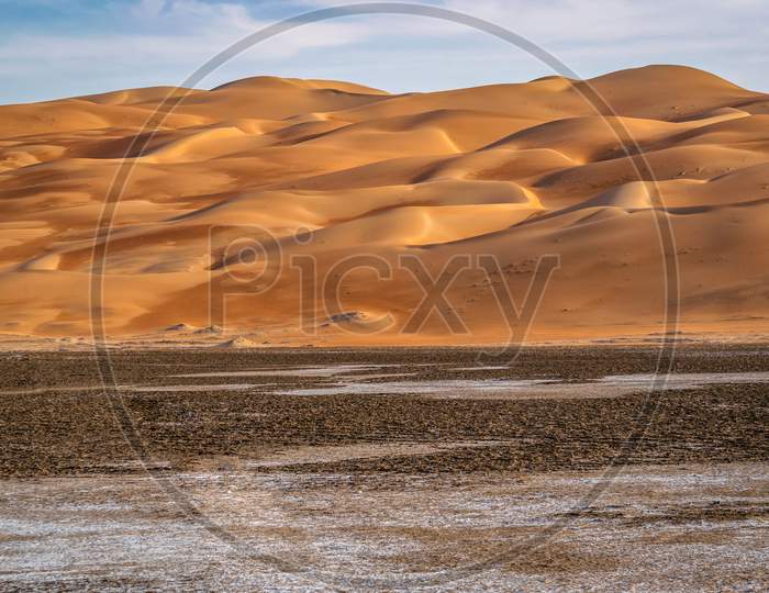 A Beautiful Valley In Liwa Desert In Abu Dhabi With Clean Sand Dunes And Blue Cloudy Sky