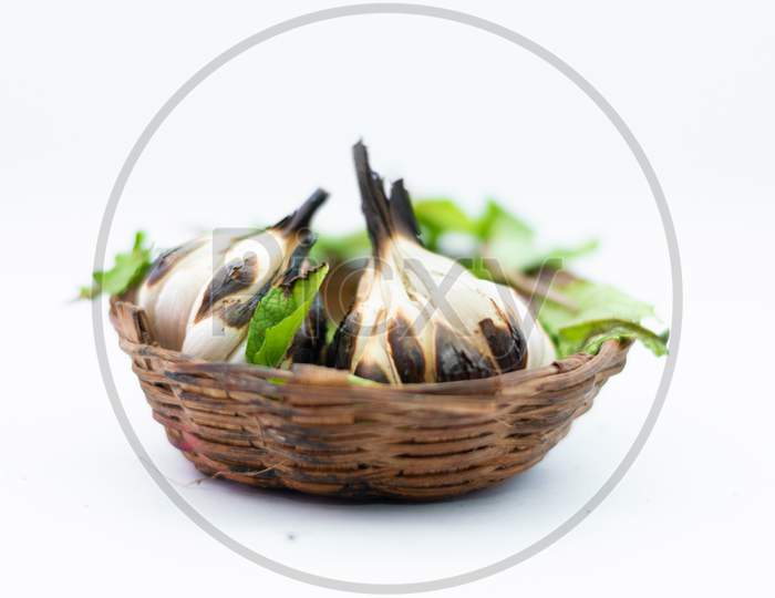 Roasted Garlic Cloves And Bulb With Green Leafs In White Background.