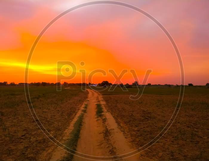 Rural Dusty Countryside Road Trough A Field With Sunset