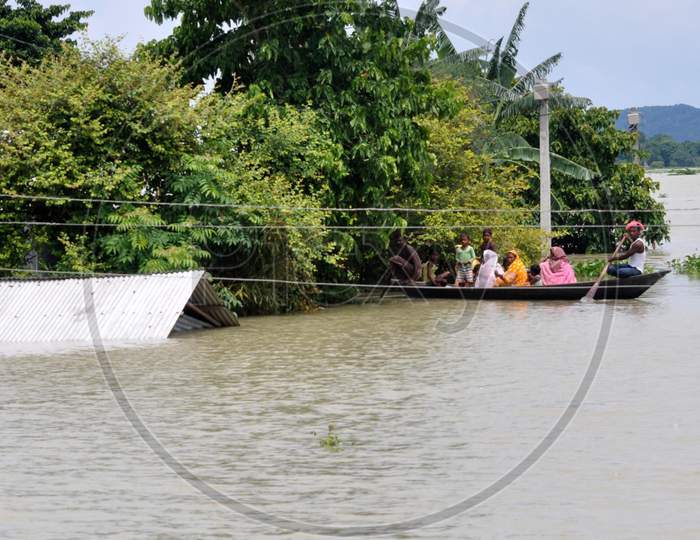 A family rows a boat to get to a safer place in the flood-affected areas in Morigaon, Assam on July 14, 2020