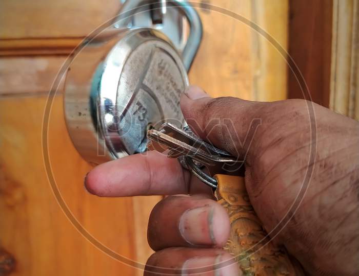 A repairman unlocking the lock with holding in dirty hand key at door opening