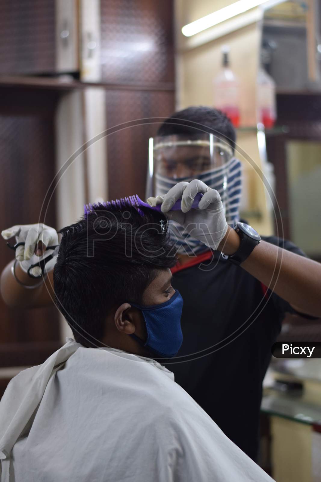 Hyderabad, Telangana, India. july-14-2020: A hairdresser, wearing a protective face mask, works in a barber shop. Reopen after Lockdown for covid-19.