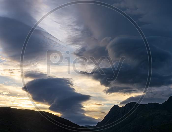 Blea Tarn And The Langdales Are Silhouetted By Cloud Formations During Sunset In The English Lake District