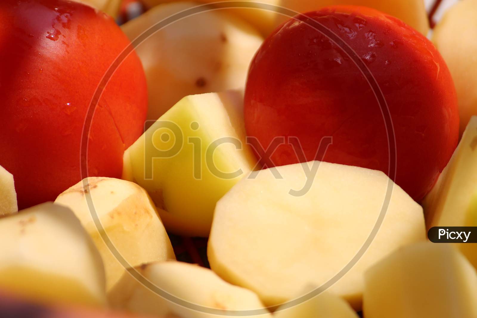 Chopped fresh potato pieces with red tomato together display ready to cook.