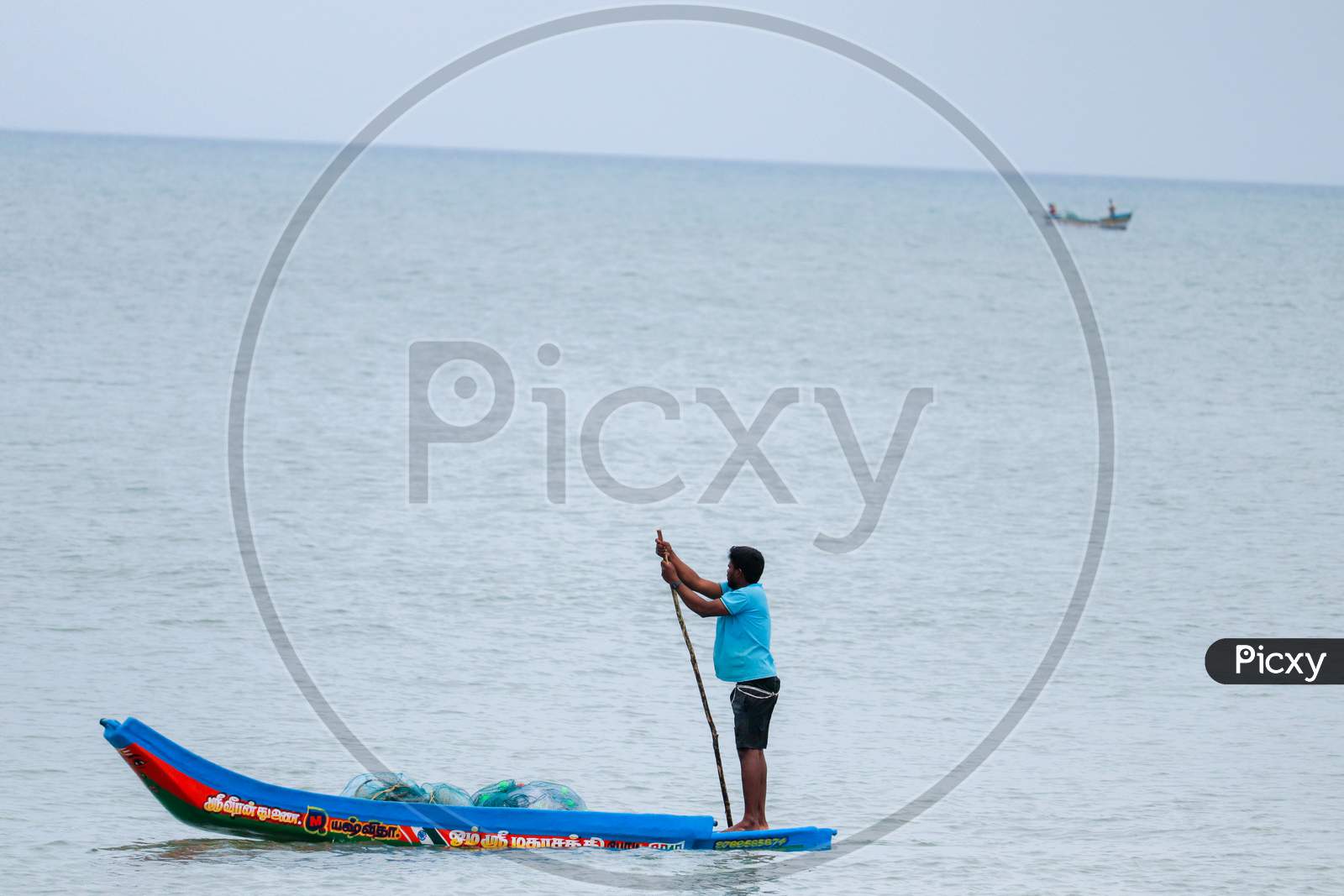 KARAIKAL, PONDICHERRY - JULY 1st 2020 - small fishing boat, fisherman holds a net to catch fish The fisherman is living in the boat most of there life.