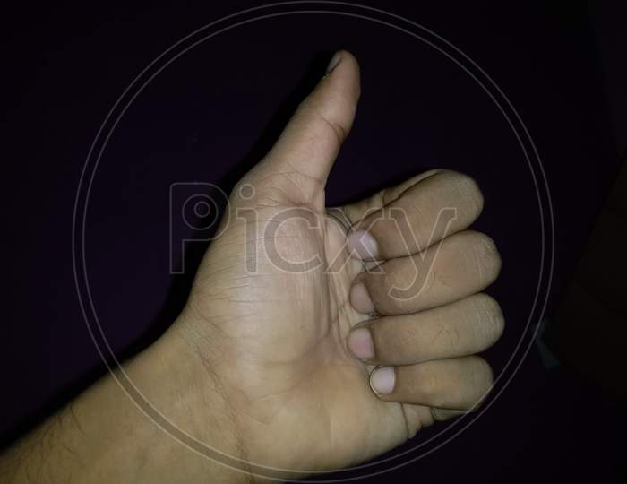 Hand of Asian man is show thumb up is symbol that Great isolated on black background.