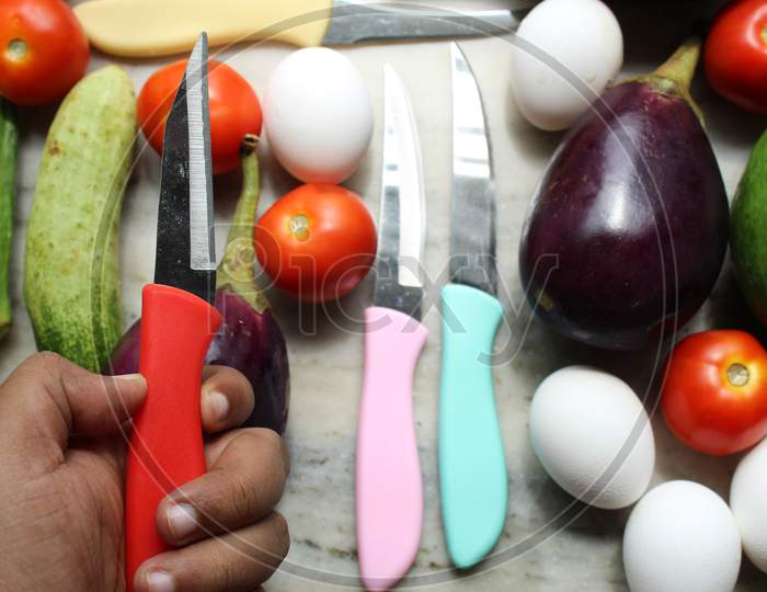 Hand holding knife and diet and health background with eggs and vegetables with selective focus.