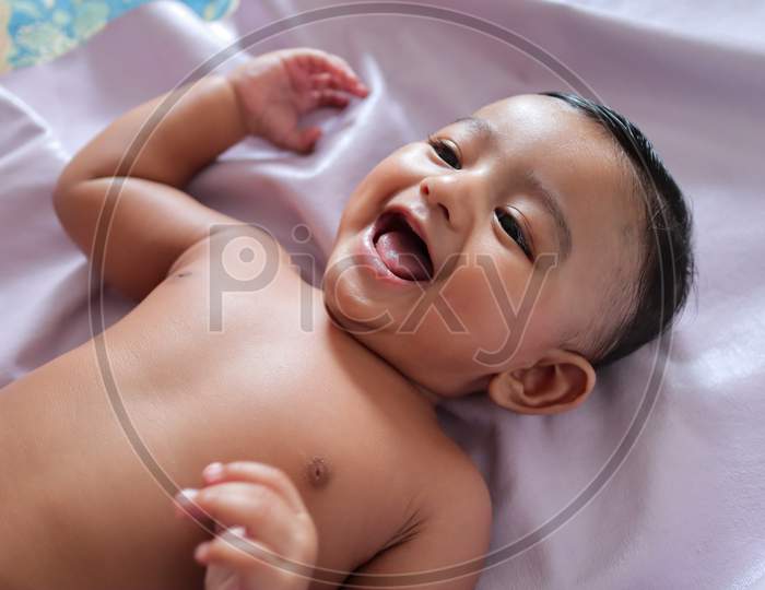 A Cute Indian Innocent New Born Baby In A Jovial Mood With A Charming Smile