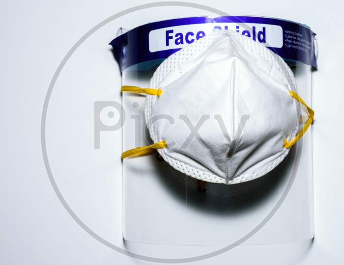 A Face Mask Covered On A Face Shield Placed On A White Surface. To Use For Personal Protection Against Covid 19