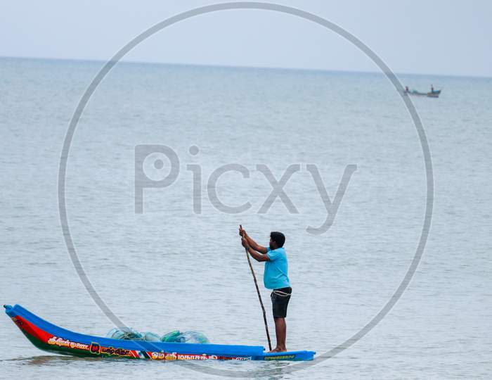 KARAIKAL, PONDICHERRY - JULY 1st 2020 - small fishing boat, fisherman holds a net to catch fish The fisherman is living in the boat most of there life.