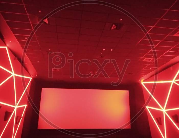 Kolkata, West Bengal/India - December 23, 2018: Red hall wall's and roof design display under dim light with movie screen inside INOX movie hall at Madhyamgram, Star Mall.