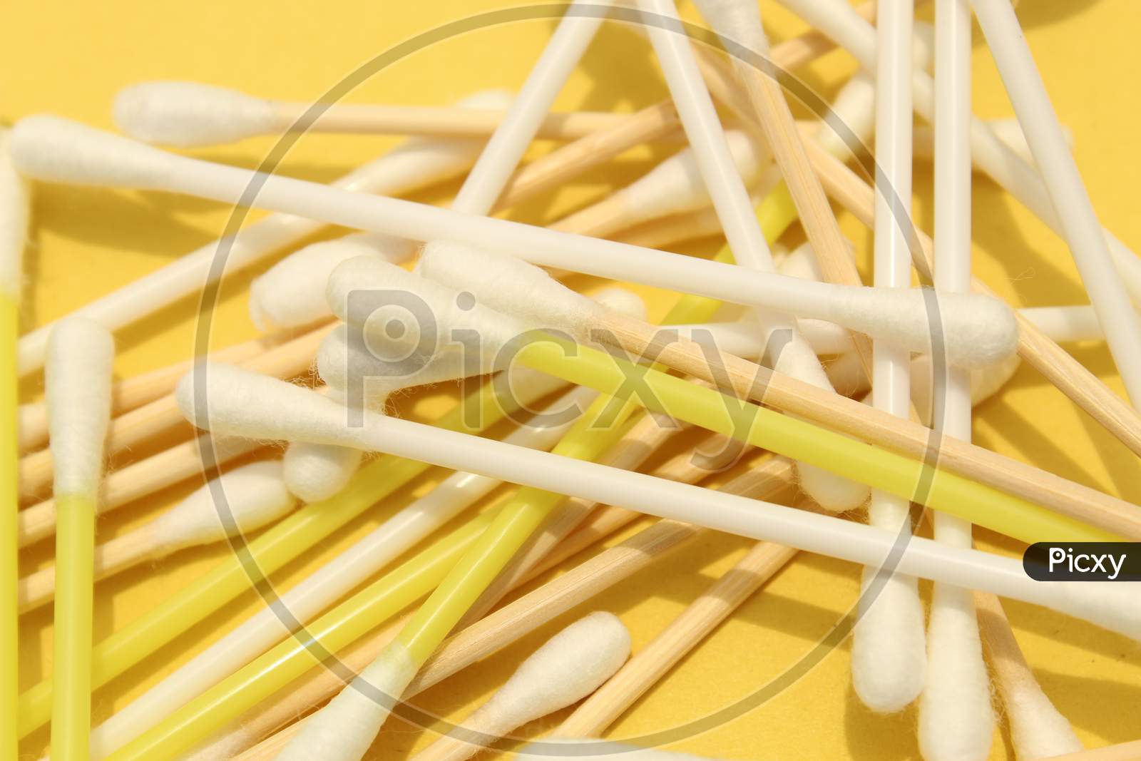 Cotton made ear buds all together close display on yellow background.